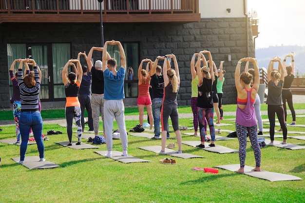 Gruppo di adulti che frequentano una lezione di yoga fuori in cortile