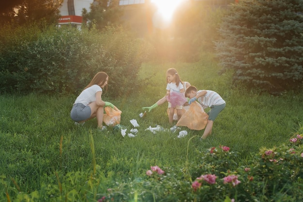 A group of adults and children together at sunset is engaged in garbage collection in the park Environmental care waste recycling Sorting garbage