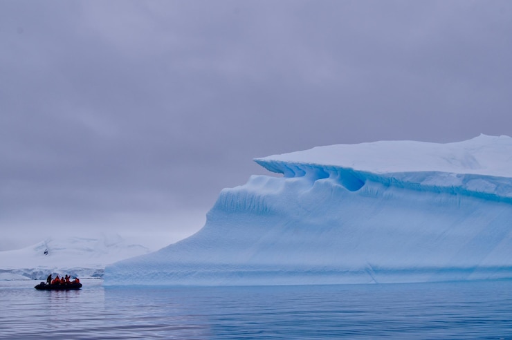 Photo group of adventures on a zodiac near a large iceberg in antarctica