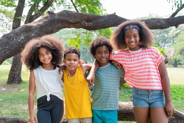 Gruppo di bambini afroamericani in piedi abbracciati insieme nel parco durante le sessioni estive