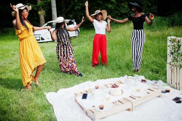 Группа афроамериканских девушек, празднующих день рождения, веселятся и танцуют на открытом воздухе с декором.