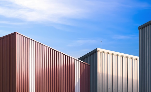 Group of aluminium industrial warehouse buildings in factory area against blue sky