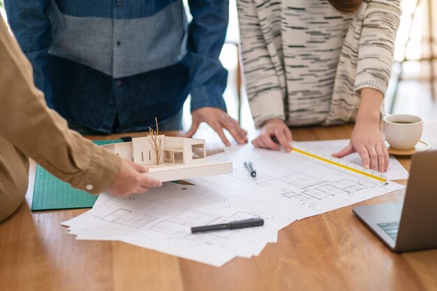 Group of an architect working and measuring scale of a mass model on table in office