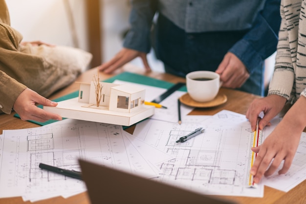 Photo group of an architect working and measuring scale of a mass model on table in office