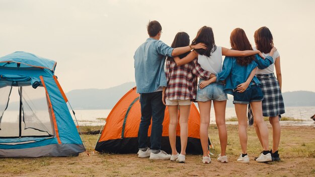 Photo group of asia best friends teenagers have fun look at nice sunset view enjoy happy moments together beside camp and tents in national park