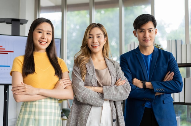 Gruppo di giovani imprenditori asiatici creativi che guardano la fotocamera e sorridono dopo il brainstorming