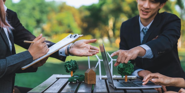 Group of asian business people presenting environmentally friendly development plan and sustainable technology project for greener future establishing outdoor eco business office at natural parkgyre