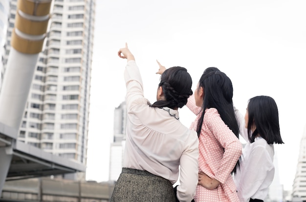 OutdoorThai女性サラリーマングループでの仕事の進捗状況のコンセプトで笑顔で前向きに指しているアジアのビジネスウーマンのグループ。