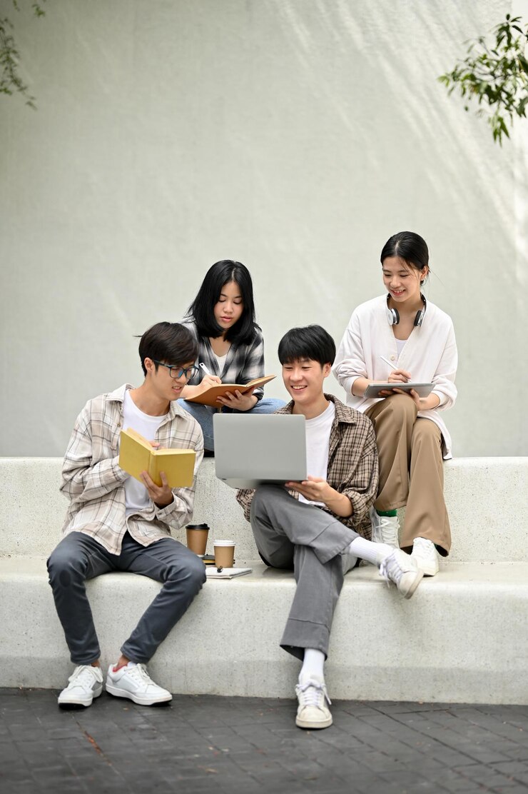 Photo 함께 숙제를 하거나 시험을 위해 과외를 하는 벤치에 앉아 있는 아시아 대학생 그룹
