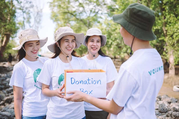 Group of asian diverse people volunteer holding a donation box for fundraiser to emergency situation such as help ukraine flood victims food for children charity eventVolunteering conceptual