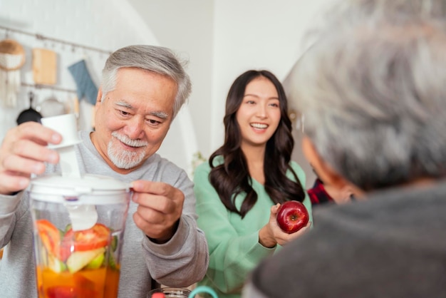 Group of asian elder senior friends at dinner party at home senior friend preparing salad and fruit juice with her daughter with smiling cheerful moment conversation with elder friend laugh smile