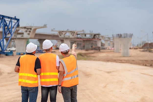 Group of asian engineers discuss about work at site of building under constructionThe contractor team discusses the design of the structureThree workers are working outside