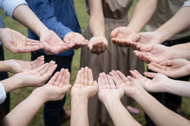 Группа азиатских людей поднимает свои правые руки и осторожно обрабатывает их, чтобы получить и поделиться добрыми чувствами вместе в обучении тимбилдингу.