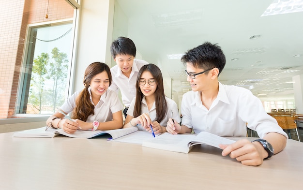 Группа в составе азиатский студент счастливый в исследовании в классе