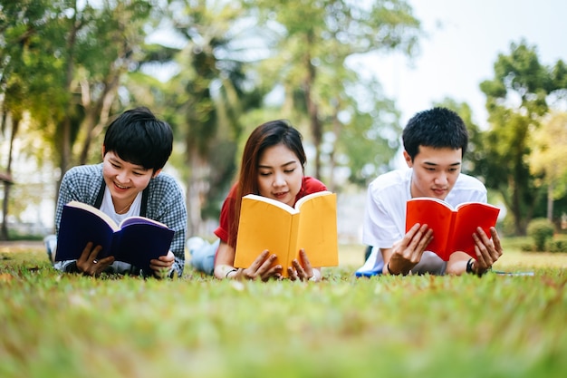 아시아 학생들의 그룹은 정원 잔디에 동시에 책을 읽으려고합니다.