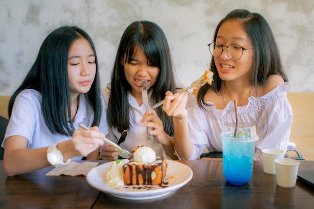 Foto gruppo di adolescenti asiatici che mangiano uno spuntino dolce nella caffetteria