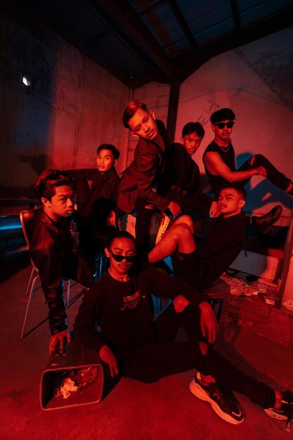 A group of Asian teenagers in black clothes posing very naughty with their friends in a warehouse with a red light