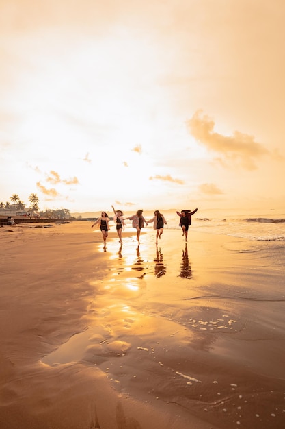 A group of Asian teenagers running with happy expressions on vacation with their friends drunk on the beach