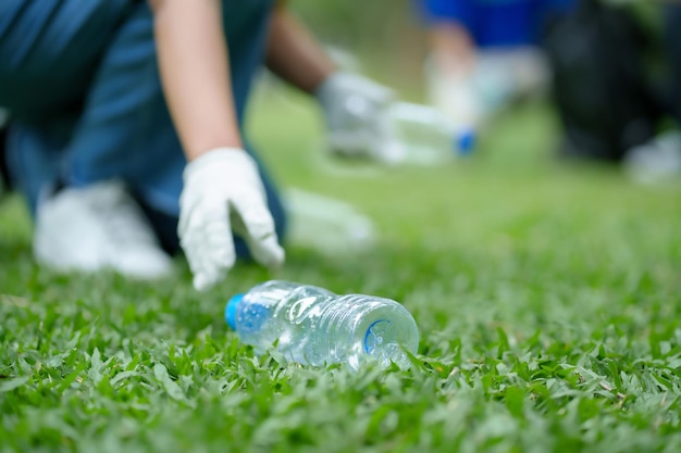 a group of asian volunteers pick up trash on the lawn after an outdoor activity
