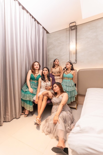 a group of Asian women in glamorous and luxurious clothes are sitting on the sofa with their friends