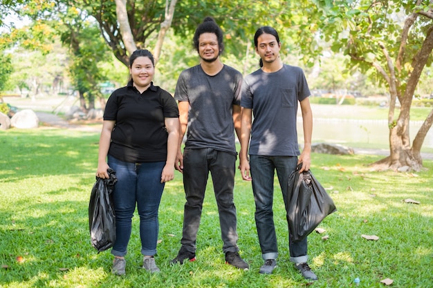 Gruppo di giovani volontari asiatici che raccolgono rifiuti in parco. concetto di protezione ambientale