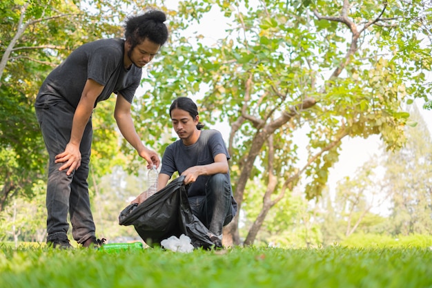 Group of Asian young volunteers picking up trash in park.