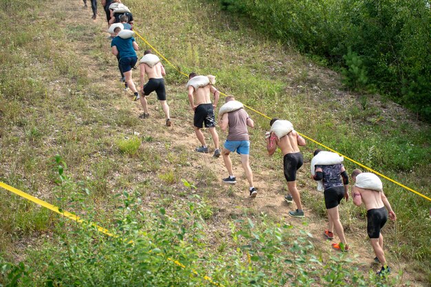 Group of athletes with bags on his shoulder climb mountain