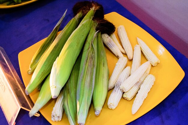 Group of baby corns with and without husk on a plate closeup shot