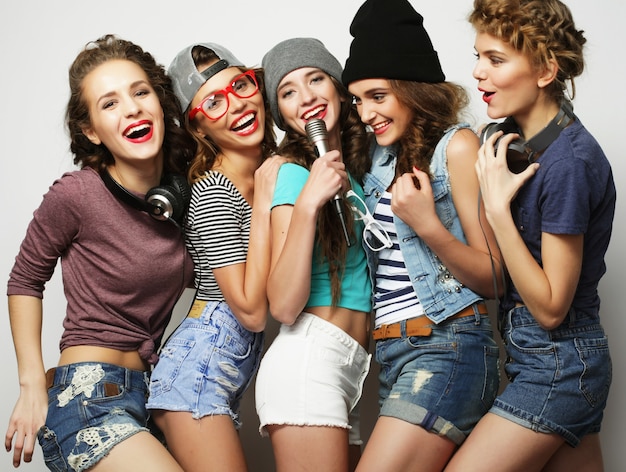 Gruppo di belle ragazze alla moda hipster che cantano al karaoke