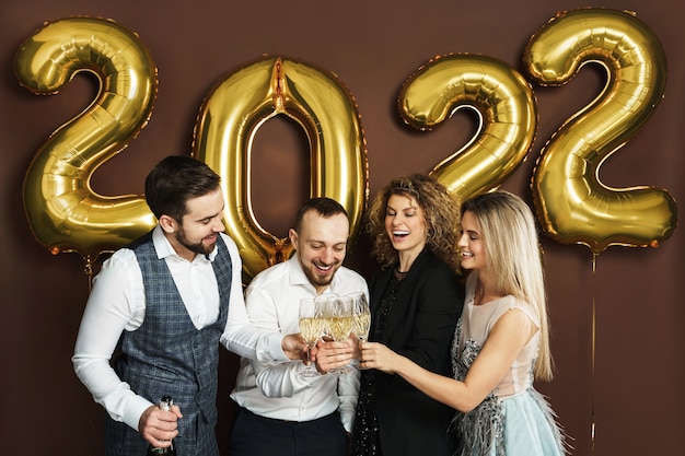 Group of beautiful well dressed party people celebrating 2022 New Year and drinking sparkling wine