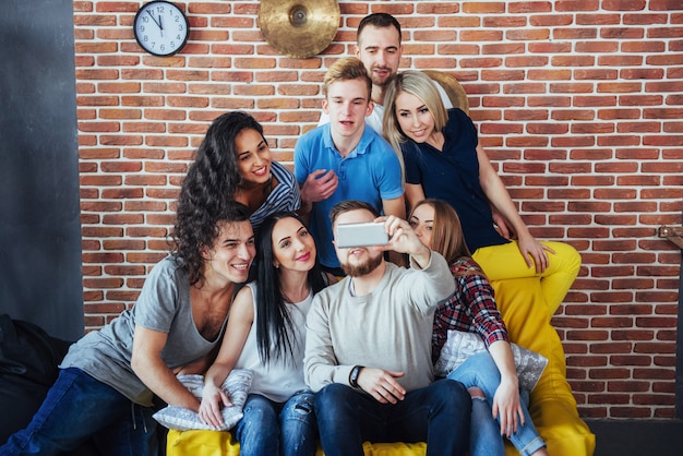 Raggruppa i bei giovani che fanno selfie in un caffè, le ragazze e i ragazzi dei migliori amici che si divertono insieme, posando uno stile di vita emotivo