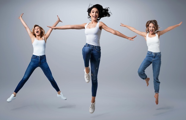 Group of beautiful  young women wearing white shirt and denim jeans having fun