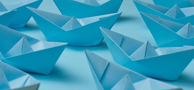 A group of blue paper boats on a blue background the concept of\
a controlled crowd