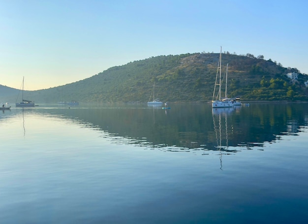 a group of boats are floating on the water with a mountain in the background