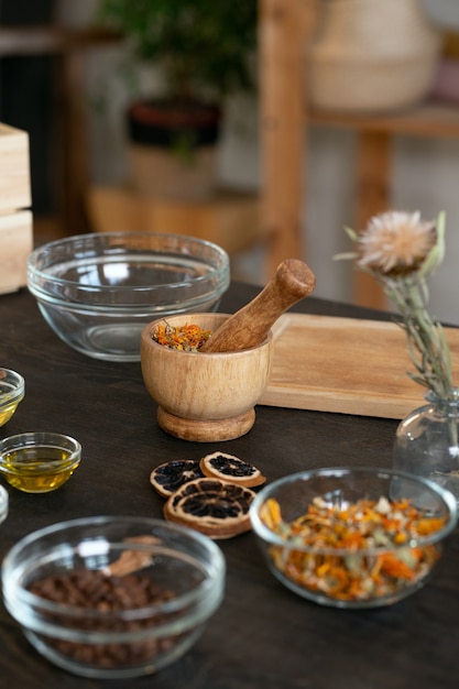 Группа мисок разного размера с эфирными маслами, кофейными зернами, сухими цветами и другими ингредиентами для приготовления натуральных косметических продуктов.