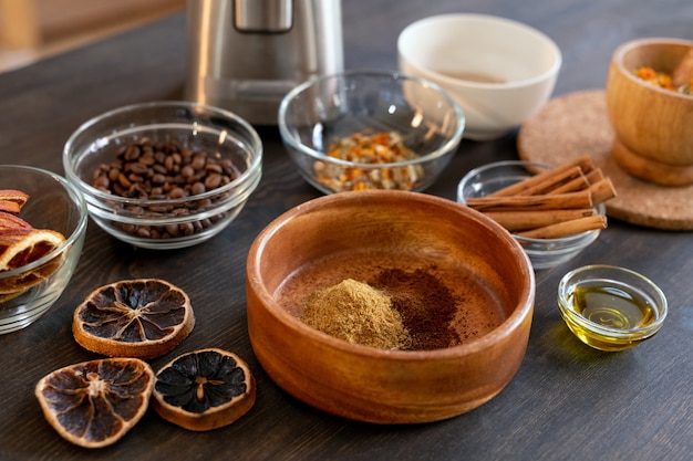 Group of bowls with coffee beans, dry flowers and orange slices, cinnamon sticks, ground candied fruits and other ingredients for making soap
