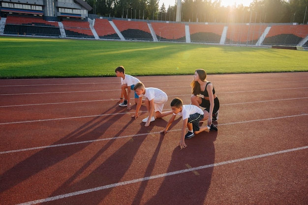 A group of boys ' children are taught by a coach at the start before running at the stadium during sunset A healthy lifestyle