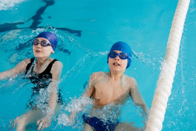 Un gruppo di ragazzi e ragazze gioca e impara a nuotare in una moderna piscina sviluppo degli sport per bambini genitorialità sana e promozione degli sport per bambini