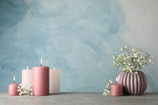 Group of burning candles and flower on blue