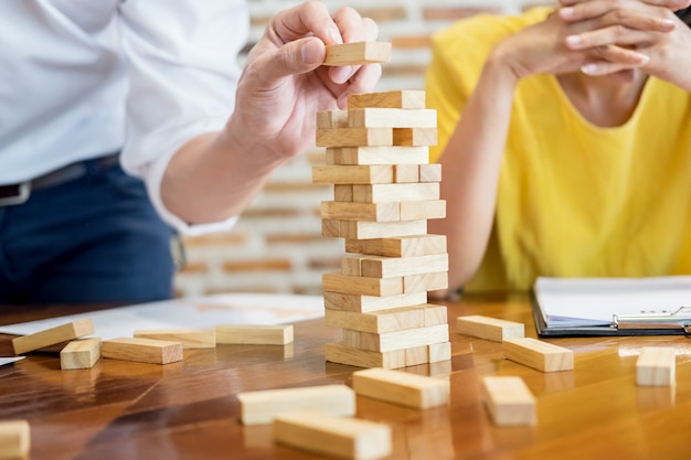 Group of business creative people building tower by wooden blocks