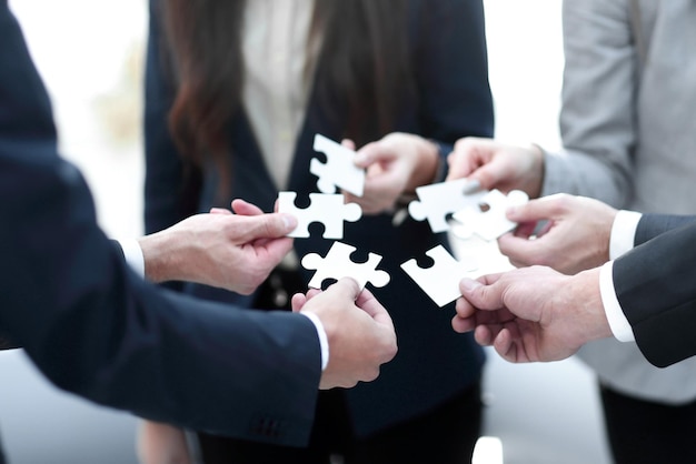 Group of business people assembling jigsaw puzzle team support