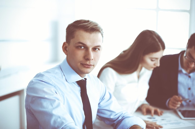 Gruppo di uomini d'affari che discutono di domande durante la riunione in un ufficio moderno. colpo in testa dell'uomo d'affari alla trattativa. concetto di lavoro di squadra, partnership e business.