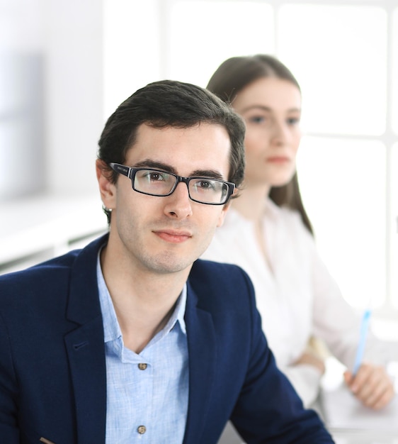 Group of business people discussing questions at meeting in modern office. Headshot of businessman at negotiation. Teamwork, partnership and business concept.