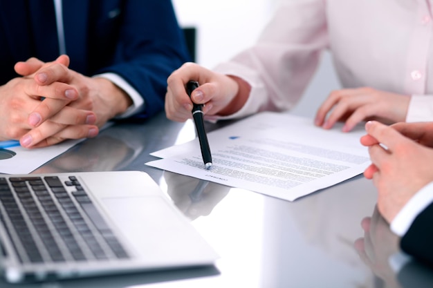 Group of business people and lawyers discussing contract papers sitting at the table, close up