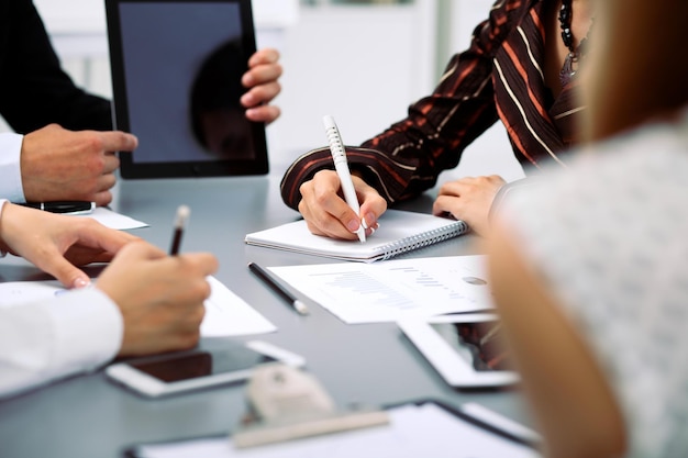 Group of business people at meeting, close up. Boss pointing into tablet computer monitor.