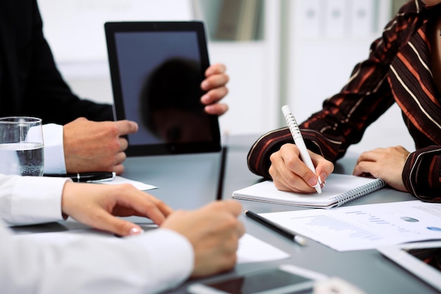 Group of business people at meeting, close up. Boss pointing into tablet computer monitor.