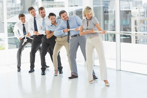 Group of business people pulling rope in office