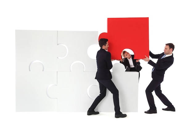 Group of business people putting new piece of jigsaw puzzle isolated on white background