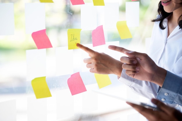 Photo group of business people putting sticky notes on glass wall at office