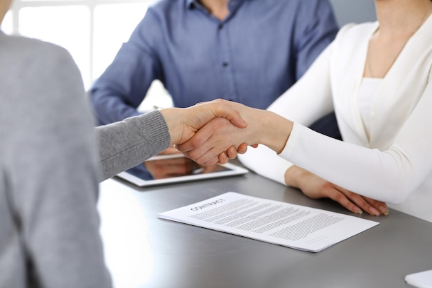 Group of business people shaking hands after discussing questions and achieving agreement at meeting in modern office. Handshake close-up. Teamwork, partnership and business concept.